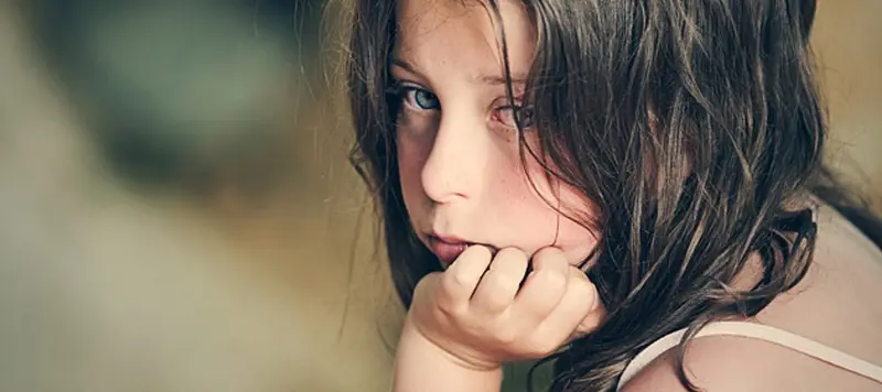 Mädchen stützt Kopf in die Hand und blickt traurig